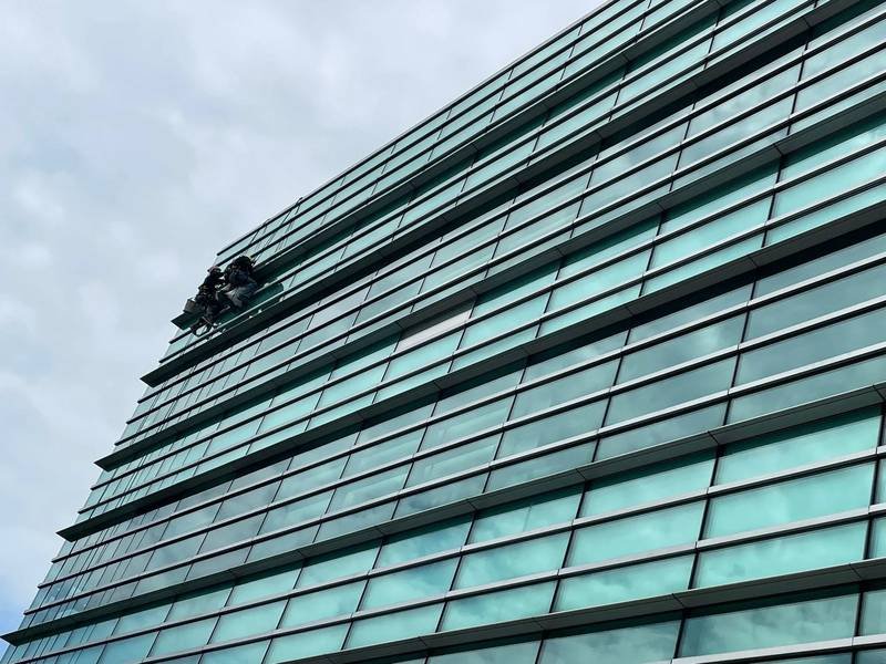 rope access technicians replacing façade glass on a green glass high-rise in Singapore
