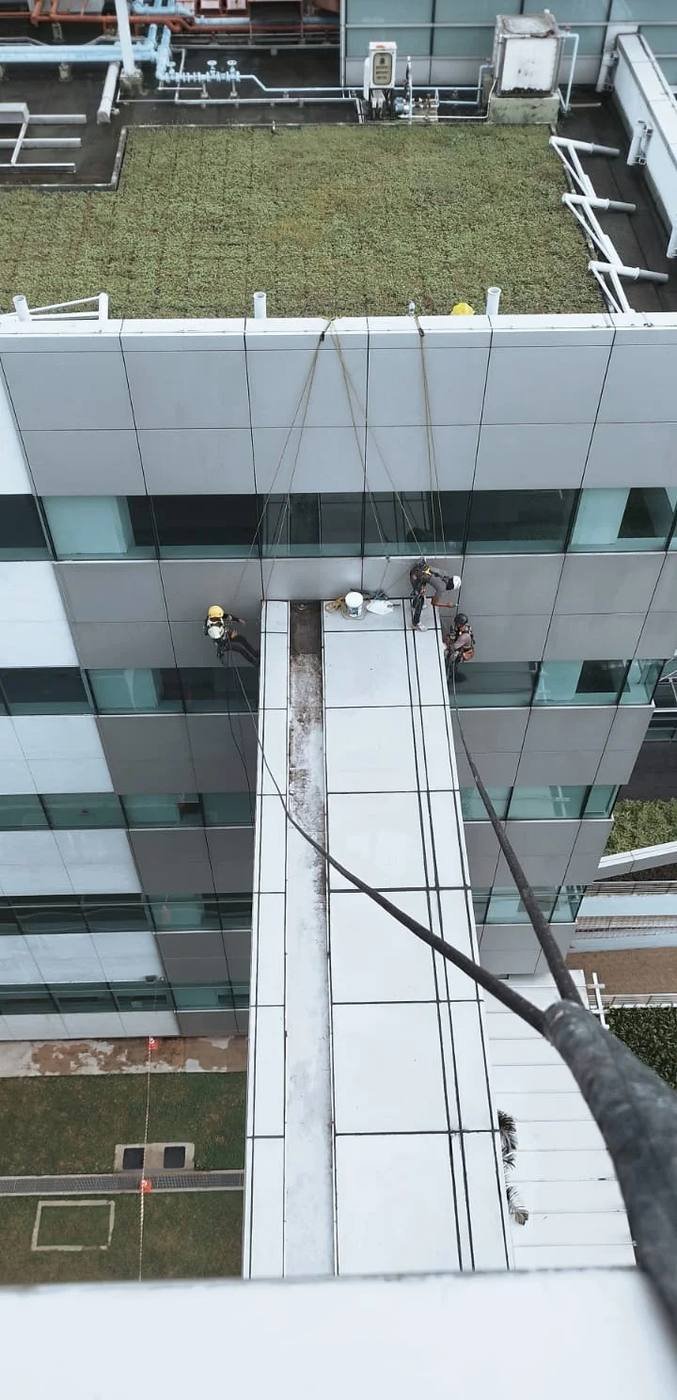 Overhead view of rope access technicians applying façade waterproofing and resealant on a Singapore building