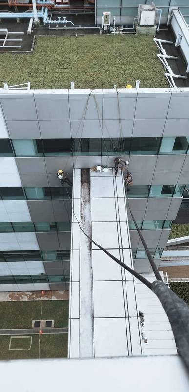 Overhead view of rope access technicians applying façade waterproofing and resealant on a Singapore building