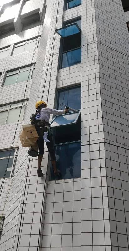 Rope access technician resealing a tiled façade window perimeter in Singapore